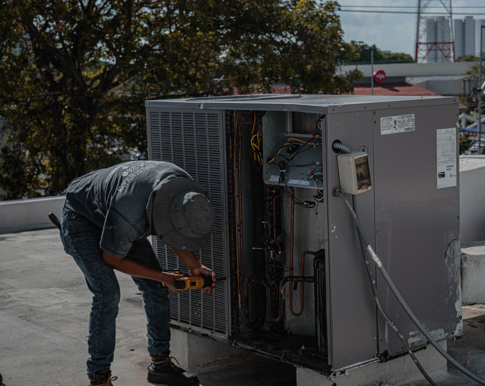 Technician repairing an outdoor air conditioning unit on a rooftop